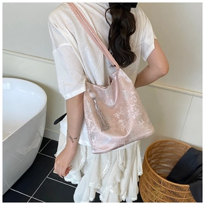 Detailed texture of pink jacquard embroidery tote bag with silk tassel worn by a model
