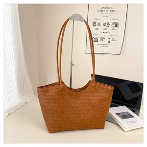 Dettaglio della trama in pelle intrecciata marrone di una borsa tote retrò minimal