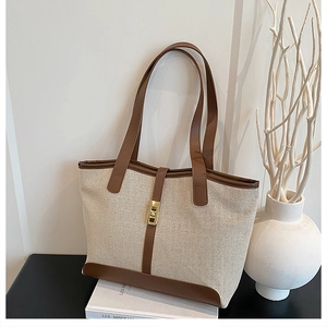 Détail du sac fourre-tout en toile beige avec bordure en similicuir marron et boucle dorée