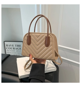 Close-up of beige chevron quilted handbag with brown handles and slim shoulder strap