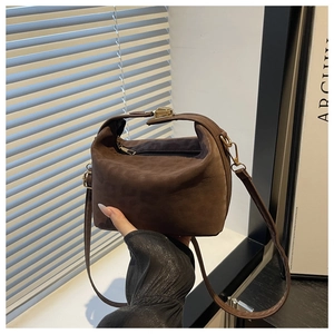 Detail of a brown suede leopard style bag with a gold metal clasp and top handle