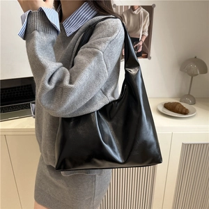 Bolso tote negro brillante minimalista para mujer mostrado en un entorno de estilo urbano