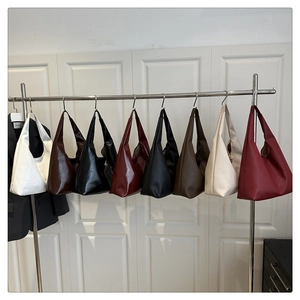 Detail view of multi-color minimalist leather tote bags hanging on a white cabinet door