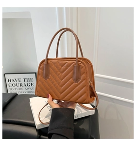 Close-up of brown quilted handbag with V-shaped stitching and gold hardware detail