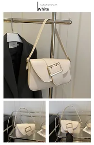 Detail of white PU leather baguette bag featuring a large gold rectangular buckle closure