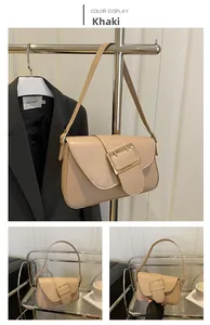 Detail view of khaki leather baguette bag with a gold buckle on a minimalist rack