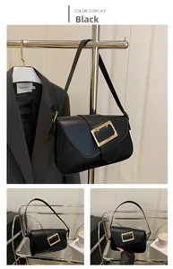 Detail view of black underarm bag with signature gold buckle and flap closure