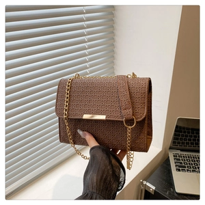 Détail du sac marron à texture tressée avec bandoulière chaîne et boucle métal