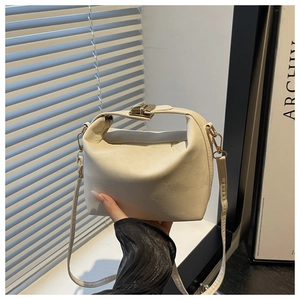 Close-up of cream PU leather handbag with gold metal lock and adjustable shoulder strap