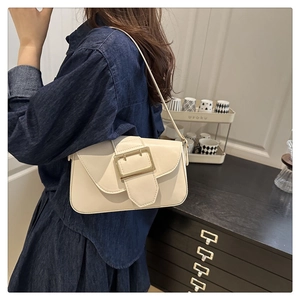 Detail of off-white baguette bag featuring a large gold metal buckle and PU leather texture