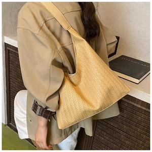 Detail of light khaki herringbone woven tote bag showing texture and wide shoulder strap