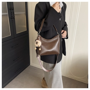 Détail du sac hobo marron foncé en cuir avec bandoulière tissée large et amovible