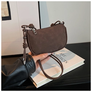 Détail d'un sac à bandoulière en daim avec zip argenté et breloque en métal carré