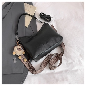 Sac croissant noir avec bandoulière à motifs et breloque mouton sur tissu blanc