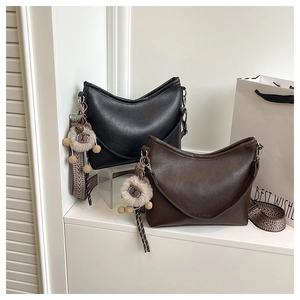 Détail de sacs hobo vintage en noir et marron foncé avec bandoulières tissées et charme en peluche
