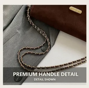 Detailed view of brown suede shoulder bag with gold chain strap and brand nameplate