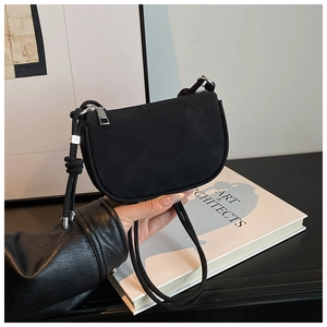 Détail du sac demi-lune en daim noir avec logo embossé et éléments métalliques argentés