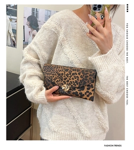 Detailed view of leopard print envelope clutch featuring a gold shield-shaped metal clasp
