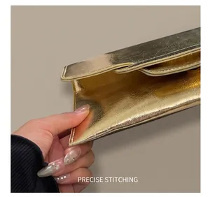 Detailansicht der präzisen Nähte an der goldenen Lederumschlagtasche mit Plissee