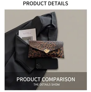 Leopard print clutch bag with heart clasp shown next to phone for size reference