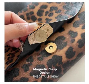 Detail of leopard print clutch showing a gold magnetic closure and smooth lining