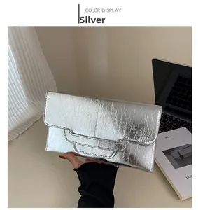 Detail der silbernen Umschlag-Clutch mit Metallic-Struktur und praktischer Handschlaufe