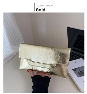 Detail der goldenen Clutch aus Leder mit Knitteroptik und praktischer Handschlaufe