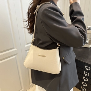 Sac bandoulière demi-lune beige chic avec décor doré et sangle réglable sur un modèle