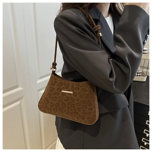 Détail du sac à main imprimé léopard avec barre en métal doré et bandoulière à nœuds