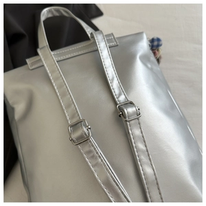 Dettaglio degli spallacci regolabili e della finitura argento di uno zaino alla moda
