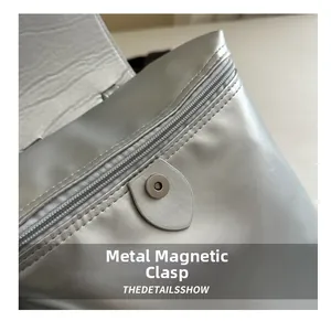 Dettaglio dello zaino metallico argento con chiusura magnetica e cerniera superiore