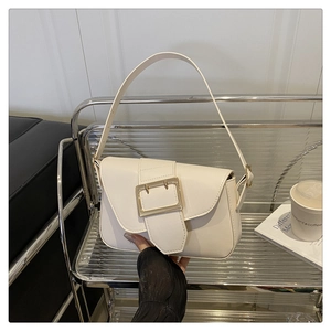 Detail of minimalist beige faux leather underarm bag featuring a bold gold buckle closure