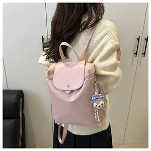 Dettaglio dello zaino in nylon rosa chiaro con spalline regolabili e ciondolo a orsetto