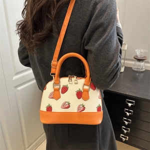 Sac à main coquille chic avec imprimé fraise et anses orange, porté en bandoulière