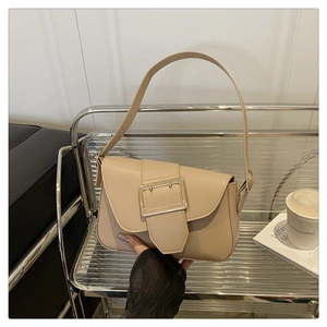 Detail of beige baguette bag with large metal buckle and adjustable strap