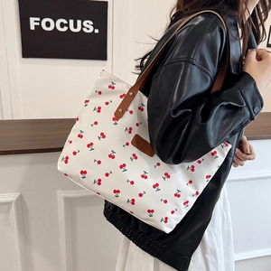 White canvas tote bag with red cherry prints and brown leather handles for women