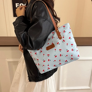 Blue tote bag with cherry print and brown leather handles for casual daily commute