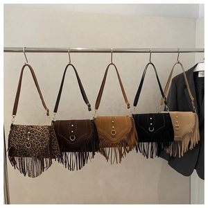 Detail view of five bohemian suede tassel shoulder bags in various colors on a rack