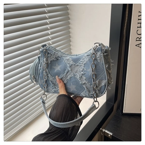 Detail of light blue denim shoulder bag with star pattern and frayed edge fringe
