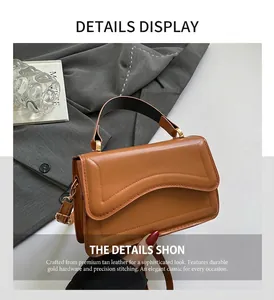 Detail of caramel brown leather handbag featuring black top handle and golden hardware