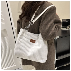 Detail of white corduroy tote bag showing textured fabric and silver chain accents