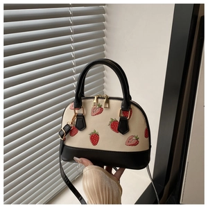 Close-up of strawberry print bag with dual metal zippers and white leather texture