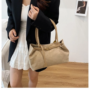 Detail shot of apricot frosted leather tote bag with metallic buckle on woman's shoulder