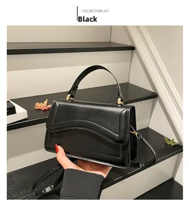 Détail du sac bandoulière noir avec bord ondulé et finitions métalliques dorées