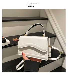 Détail du sac blanc montrant la texture matelassée ondulée et les ferrures dorées
