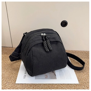Close-up of black corduroy messenger bag featuring dual woven zipper pullers and texture