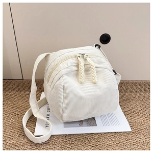 Detail of white corduroy shell bag showing dual zippers and braided rope pulls