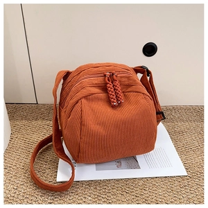 Detail of orange corduroy shell bag showing dual zippers and thick ribbed fabric texture