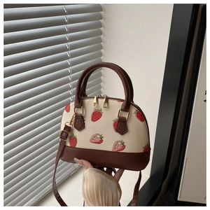 Close-up of strawberry print shell bag featuring gold hardware and dual zipper closure