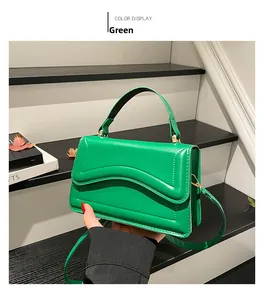 Detail of green glossy leather handbag with wavy stitching and detachable strap